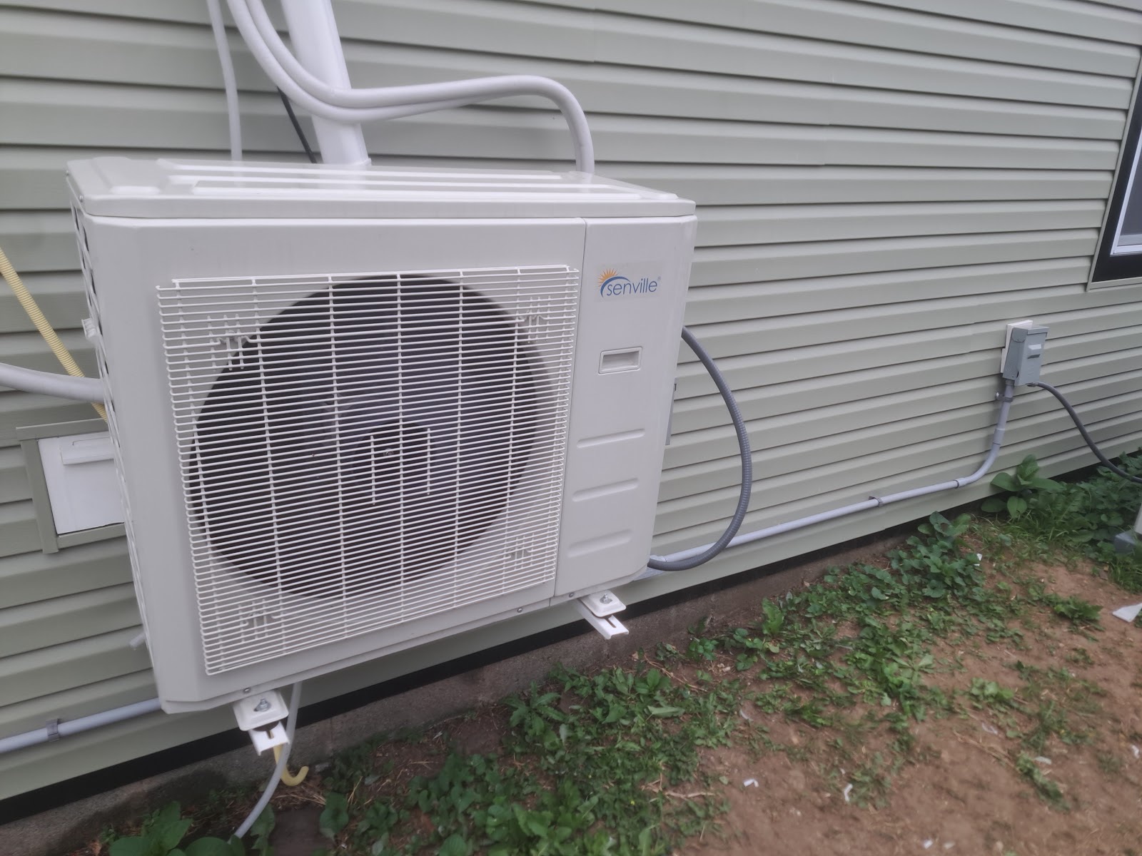 Outdoor mini-split unit mounted against vinyl siding